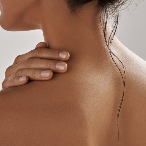 Mujer aplicando se crema corporal en cuello