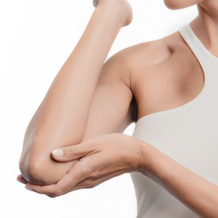 Mujer hidratandose los codos con producto bioderma